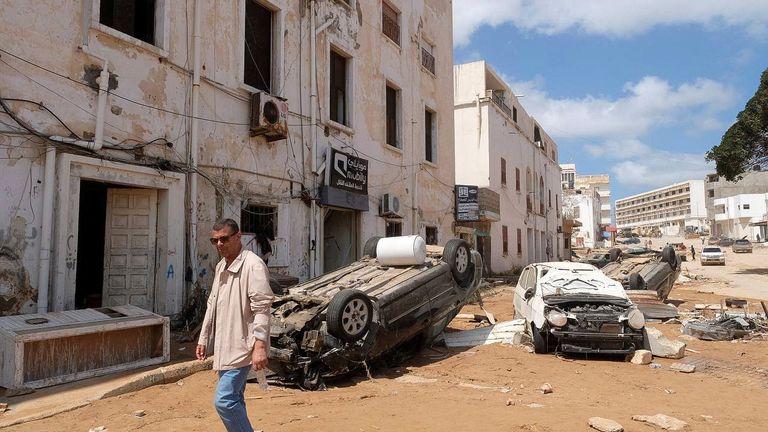 A man walks in front of the damaged cars, after a powerful storm and heavy rainfall hit Libya, in Derna, Libya 