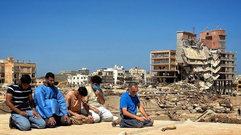 Men pray between digging