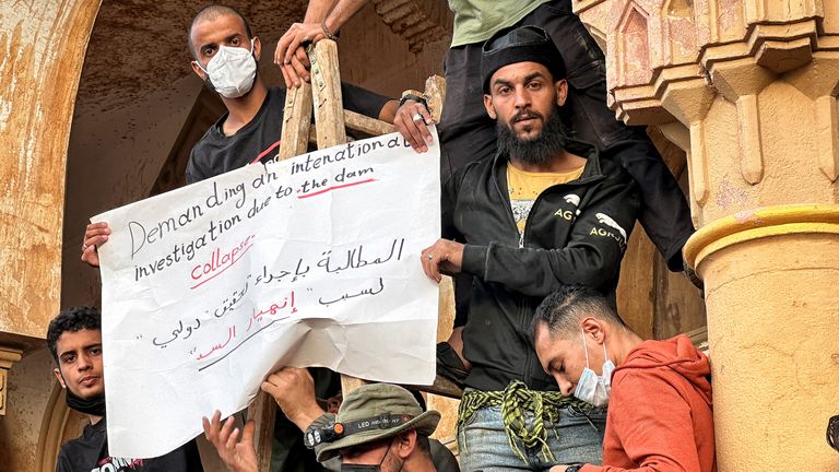 Protesters hold a sign written in English and Arabic