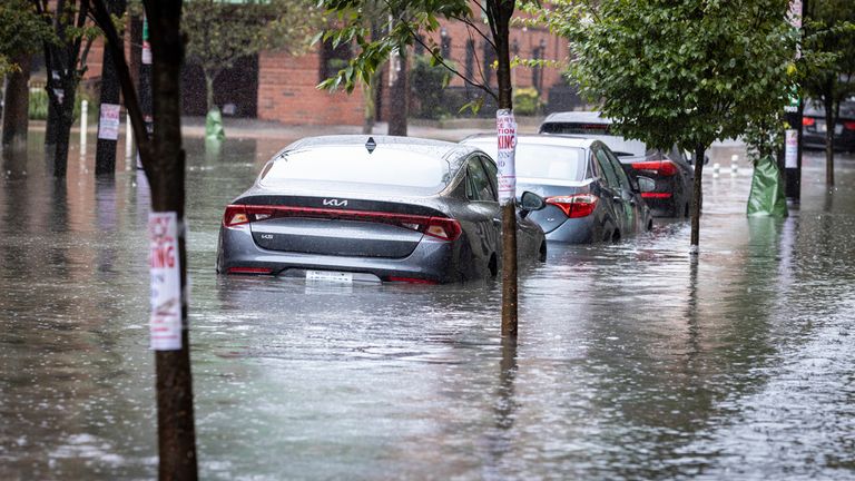 Cars sit parked in deep water as heavy rains cause streets to flood