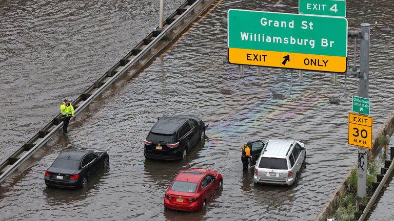 Police officers assist motorists stuck on a flooded street after heavy rains 