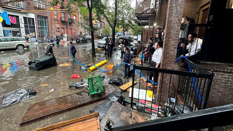 Residents watch as workers attempt to clear a drain in flood waters