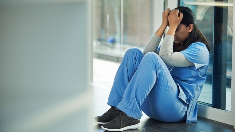 Shot of a young doctor sitting on the floor and looking distraught

