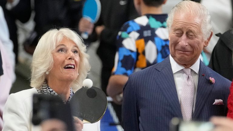 Queen Camilla plays table tennis as King Charles looks on during a visit to a gymnasium Thursday in Saint-Denis, outside Paris 