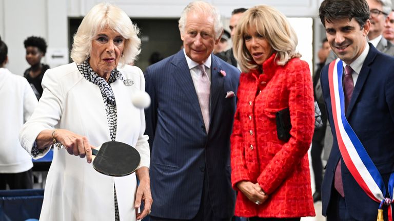 Queen Camilla plays table tennis as King Charles   and Brigitte Macron, and mayor of Saint-Denis Mathieu Hanotin  watch during a visit to a gymnasium in in Saint-Denis