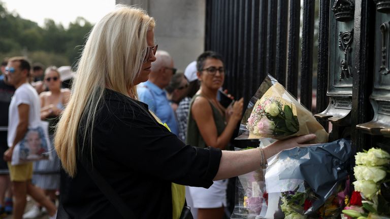 A woman lays flowers outside the Buckingham Palace on the first anniversary of Queen Elizabeth II&#39;s death