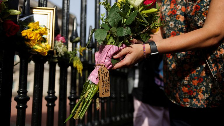 A woman lays flowers outside Buckingham Palace on the first anniversary of Queen Elizabeth II&#39;s death