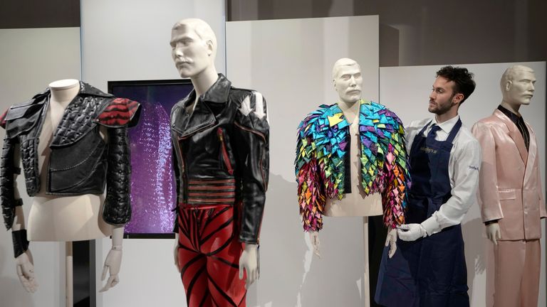 A Sotheby&#39;s handler displays a &#39;Rainbow Coloured Satin Arrow Applique Jacket from 1982&#39; at Sotheby&#39;s auction rooms in London, Thursday, Aug. 3, 2023. More than 1,000 of Freddie Mercury&#39;s personal items, including his flamboyant stage costumes, handwritten drafts of "Bohemian Rhapsody" and the baby grand piano he used to compose Queen&#39;s greatest hits, are going on show in an exhibition at Sotheby&#39;s London ahead of their sale. (AP Photo/Kirsty Wigglesworth)