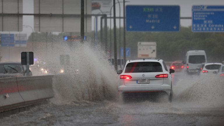 A vehicle passes through a large puddle of water in Madrid