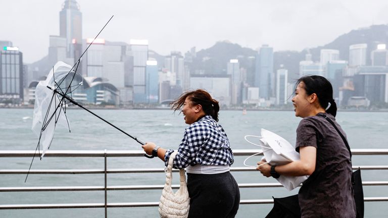 A woman holds a broken umbrella as Super Typhoon Saola approaches, in Hong Kong, China September 1, 2023. REUTERS/Tyrone Siu