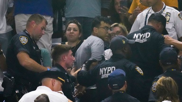 New York police officers escort a protester out of the crowd after a disruption in play between Coco Gauff, of the United States, and Karolina Muchova, of the Czech Republic, during the women&#39;s singles semifinals of the U.S. Open tennis championships, Thursday, Sept. 7, 2023, in New York. (AP Photo/Charles Krupa)