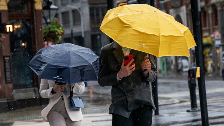 People walk through the rain and wet weather in Victoria, London