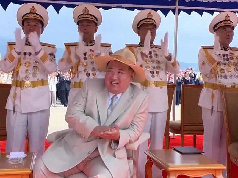 Kim Jong Un swaps hats as he watches submarine launch.