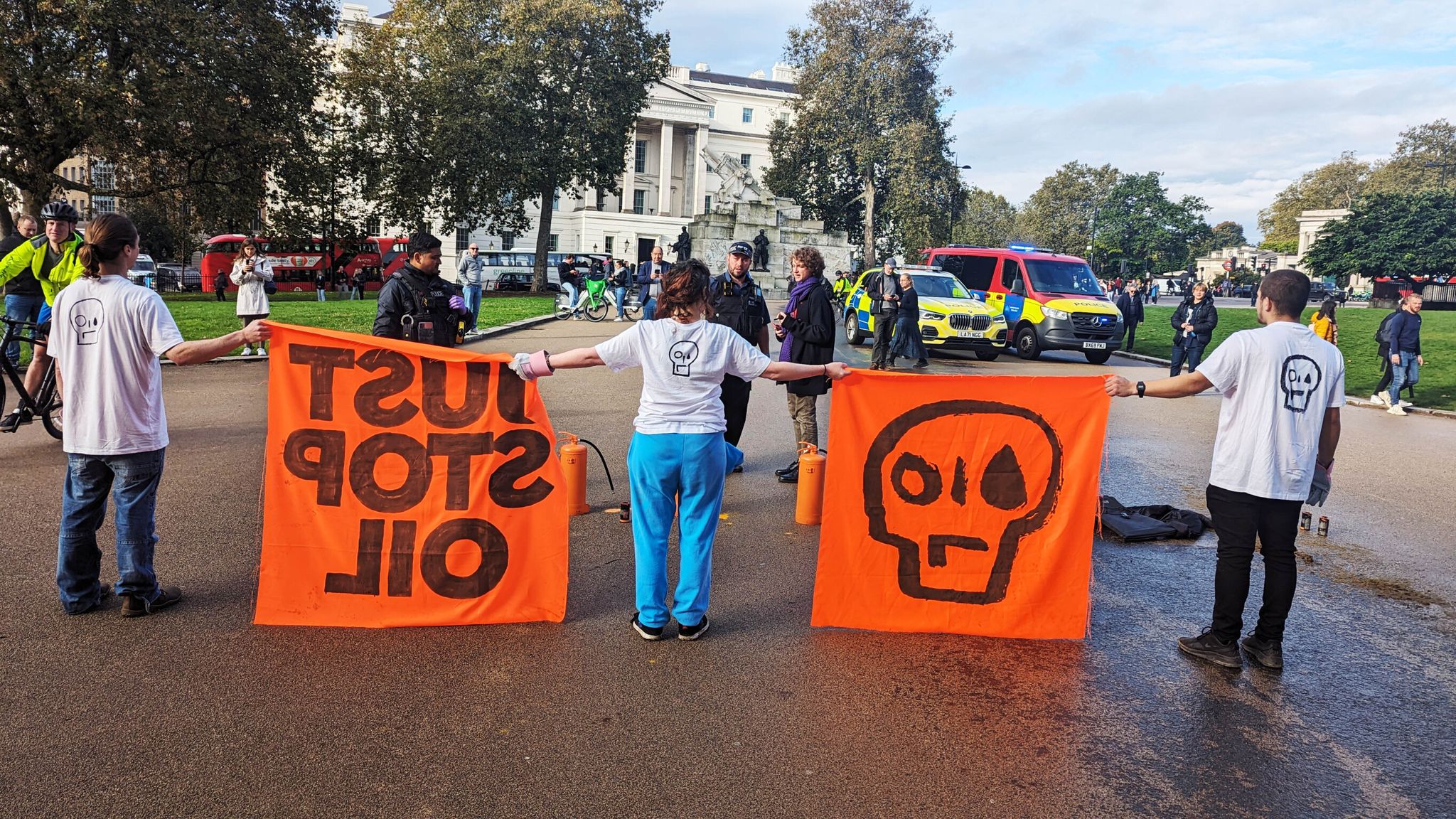 Protesters hold large orange banners reading 