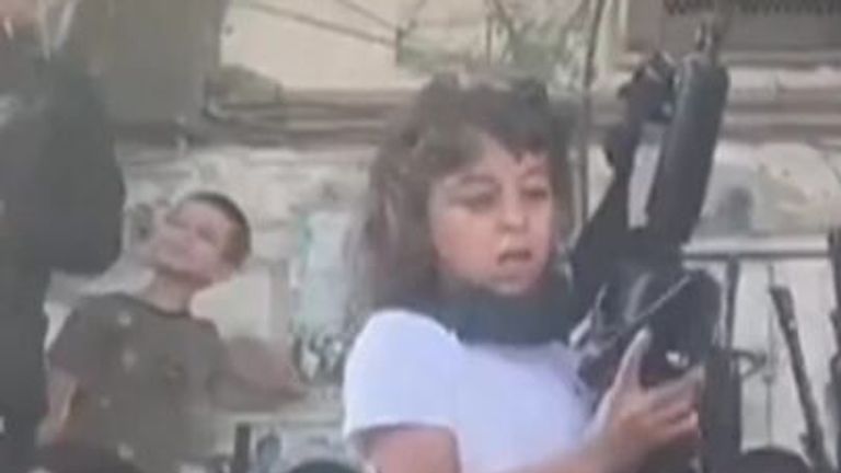 A girl in Jenin refugee camp holds two guns