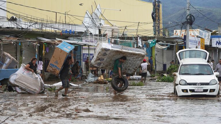 People walk with goods looted from a shopping mall after Hurricane Otis ripped through Acapulco 