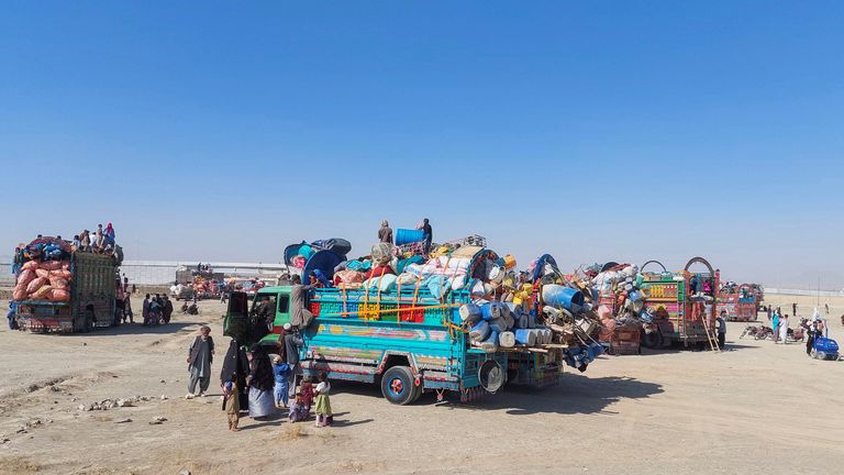 An Afghan family stands by their truck, loaded with belongings as they along with others are returning home, 