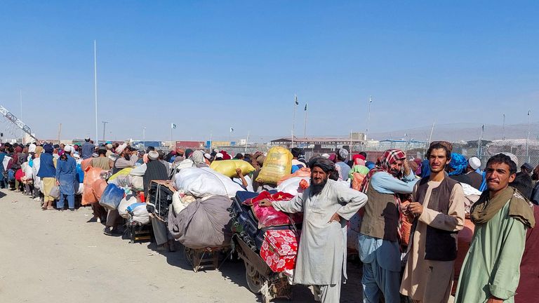 Afghan citizens wait with their belongings to cross into Afghanistan