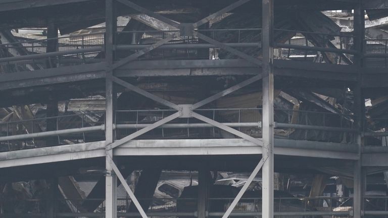The burnt out shells of cars, buried amongst debris of a multi-storey car park at Luton Airport 