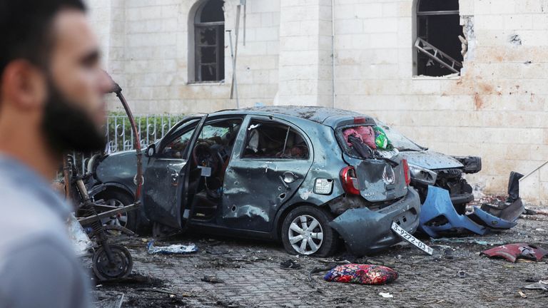 A man stands next to a damaged car in the area of  al Ahli hospital where hundreds of Palestinians were killed in a blast that Israeli and Palestinian officials blamed on each other, and where Palestinians who fled their homes were sheltering amid the ongoing conflict with Israel,  in Gaza City, October 18, 2023.  REUTERS/Mohammed Al-Masri