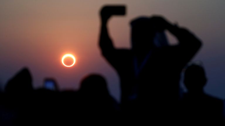 People take photos with their smartphones as they monitor an annular solar eclipse in Saudi Arabia, December in 2019