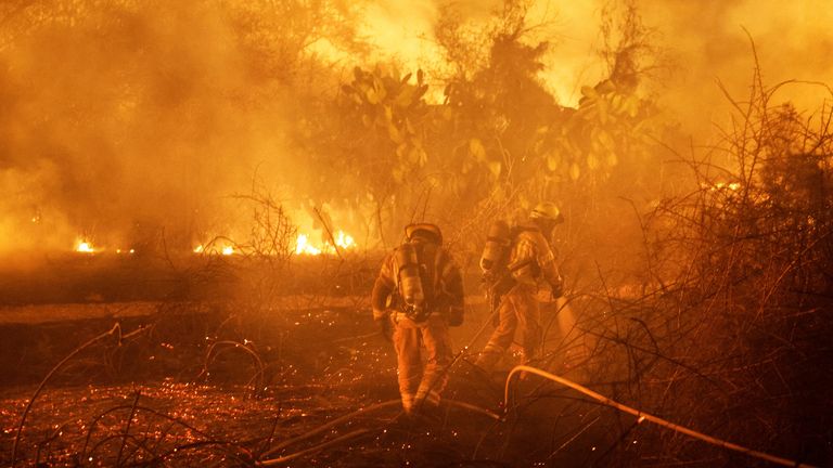 Firefighters work to put out a fire in an open field in Ashkelon, Israel, following a mass-infiltration by Hamas