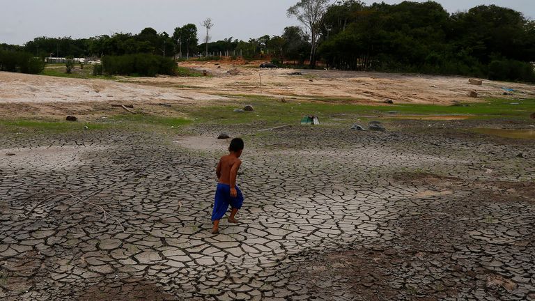 A little boy walks across a dry, cracked area of the Negro River near his houseboat during a drought in Manaus, Amazonas state, Brazil, Monday, Oct. 16, 2023. The Amazon...s second largest tributary on Monday reached its lowest level since official measurements began near Manaus more than 120 years ago. (AP Photo/Edmar Barros)