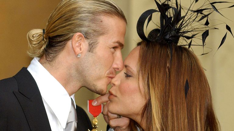 David Beckham kisses his wife, Victoria, as he holds the OBE 
Pic:AP