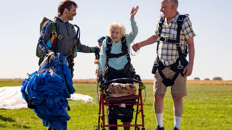 CORRECTS ID TO DANIEL WILSEY NOT DEREK BAXTER Dorothy Hoffner, 104, waves to the crowd with Daniel Wilsey, left, and friend Joe Conant after becoming the oldest person in the world to skydive Sunday, Oct. 1, 2023, at Skydive Chicago in Ottawa, Ill. (Brian Cassella/Chicago Tribune via AP)