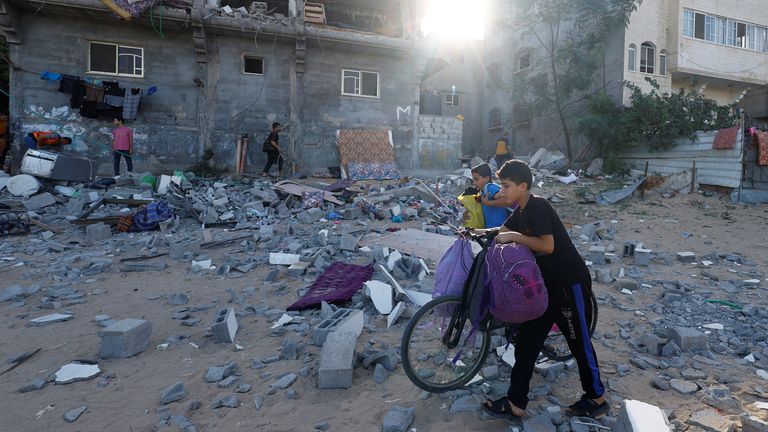 Young Palestinians walk in front of a damaged building in the aftermath of Israeli strikes, amid the ongoing conflict between Israel and Palestinian Islamist group Hamas, in Khan Younis in the southern Gaza Strip, October 30, 2023. REUTERS/Mohammed Salem