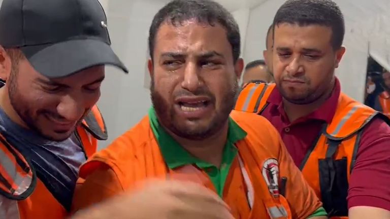 Men in a Gaza hospital gathered around a gurney, crying while holding the man laid in front of them