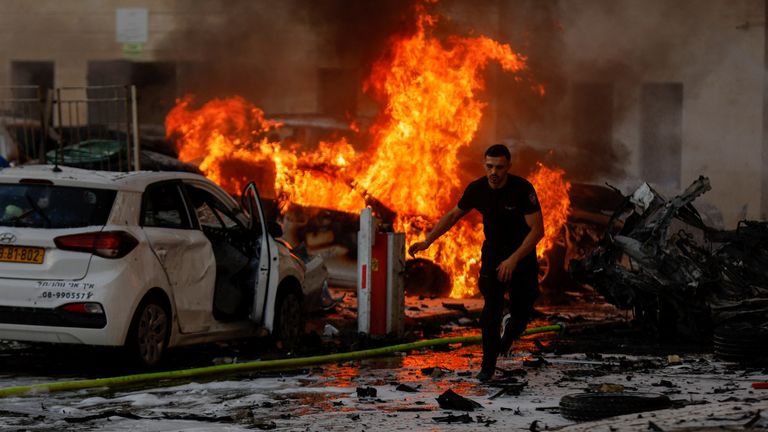 A man runs on a road as fire burns after rockets were launched from the Gaza Strip, in Ashkelon, Israel October 7, 2023. REUTERS/Amir Cohen
