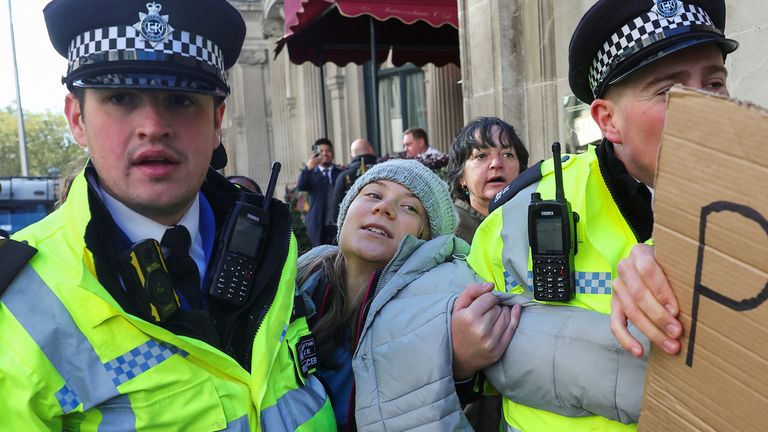 Police officers detain Swedish climate campaigner Greta Thunberg during a protest in London