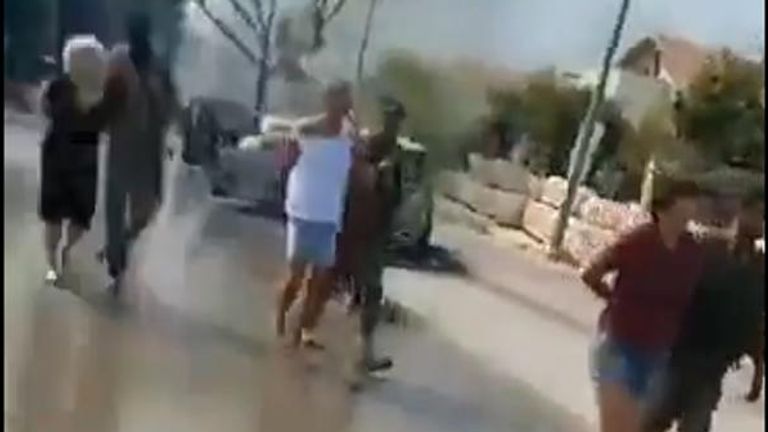 Video from the village of Be&#39;eri, where handcuffed men and women in civilian clothing are seen being led away by armed men.