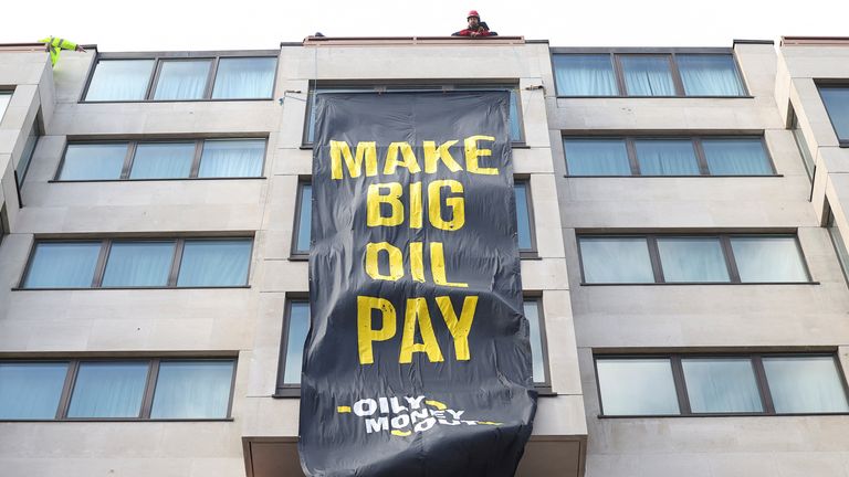 Climate activists attach a banner on the outside of the InterContinental London Hotel, where the Energy Intelligence Forum is taking place, as climate activists attend an Oily Money Out and Fossil Free London protest in London, Britain, October 17, 2023. REUTERS/Toby Melville