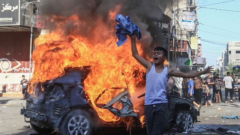 A Palestinian boy reacts next to a burning Israeli vehicle that Palestinian gunmen brought to Gaza after they infiltrated areas of southern Israel, in the northern Gaza Strip October 7, 2023. REUTERS/Mahmoud Issa NO RESALES. NO ARCHIVES.