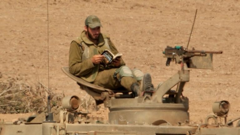 An Israeli soldier reads a book as he awaits orders