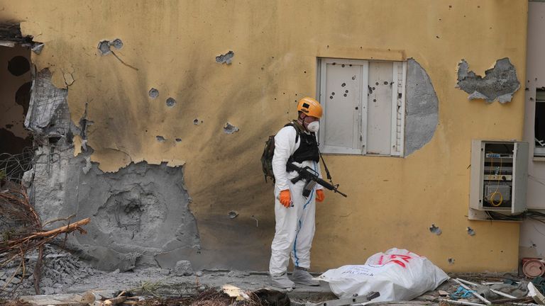 An Israeli soldier stands over the body of a Hamas militant in Beeri. Pic: AP