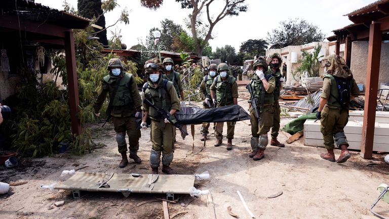 Israeli soldiers carry the body of a victim of an attack by militants from Gaza at Kibbutz Kfar Aza, in southern Israel, October 10, 2023. REUTERS/Ronen Zvulun