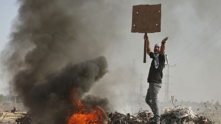 A Palestinian protester holding a sign shouts during clashes with Israeli troops near the border with Israel, in the east of Gaza City October 16, 2015. The unrest that has engulfed Jerusalem and the occupied West Bank, the most serious in years, has claimed the lives of 34 Palestinians and seven Israelis. The tension has been triggered in part by Palestinians&#39; anger over what they see as increased Jewish encroachment on Jerusalem&#39;s al-Aqsa mosque compound, which is also revered by Jews as the l