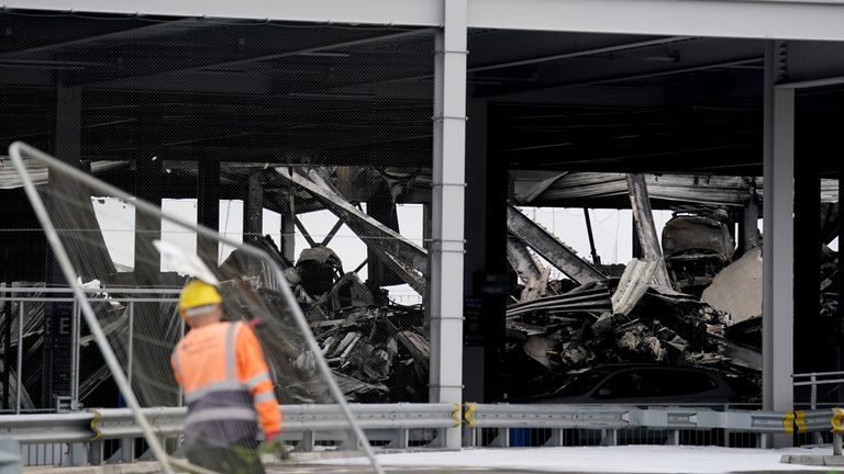 The burnt out shells of cars, buried amongst debris of a multi-storey car park at Luton Airport 
