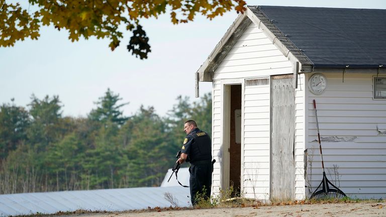 A police officer keeps watch during a manhunt at a farm for the suspect in this week&#39;s deadly mass shootings, Friday, Oct. 27, 2023, in Lisbon, Maine. Police are still searching for the man who killed at least 18 in separate shootings at a bowling alley and restaurant in Lewiston on Wednesday. (AP Photo/Robert F. Bukaty)