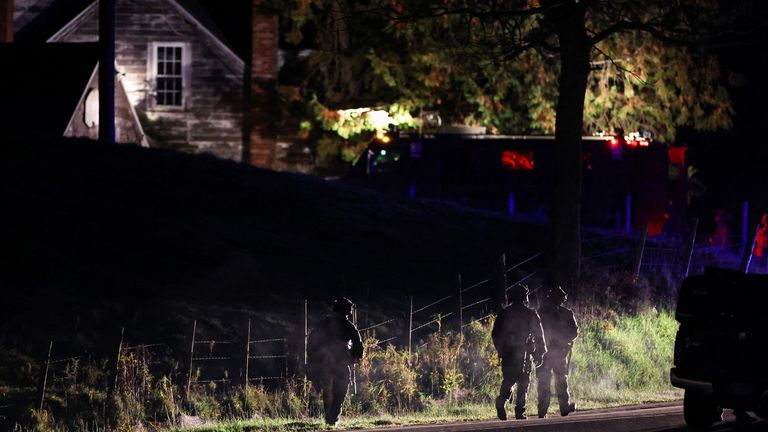Law enforcement personnel surround a house in Bowdoin as they search for the suspect in the mass shootings in Lewiston, Maine 