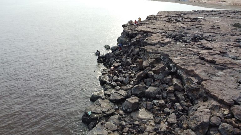 People are seen in the area where ancient stone carvings on a rocky point of the Amazon river were exposed after water levels dropped to record lows during a drought in Manaus, Amazonas state, Brazil October 23, 2023. REUTERS/Suamy Beydoun
