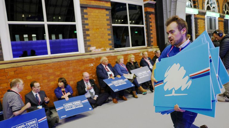 People are handed placards as they wait at the venue for the Conservative Party&#39;s conference in Manchester