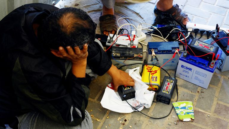 Palestinians charge their mobile phones from a point powered by solar panels in Khan Younis