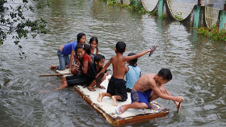 Children ride on a makeshift raft after flooding on the southern Philippine island of Mindanao