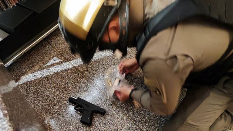 A police officer collects a gun following shots fired at the luxury Siam Paragon shopping mall, in Bangkok, Thailand
Pic: Thai rescue workers association/Reuters