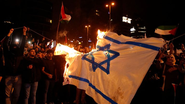 Demonstrators set fire to a makeshift Israeli flag during a protes