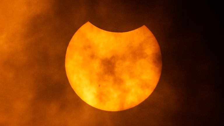 The moon is seen behind clouds as it begins to move in front of the sun during an annular solar eclipse, or ring of fire, Saturday, Oct. 14, 2023, as seen from San Antonio. (AP Photo/Eric Gay)